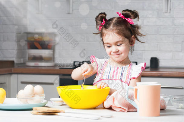 漂亮的小的女孩面包师向厨房和烘焙组成部分