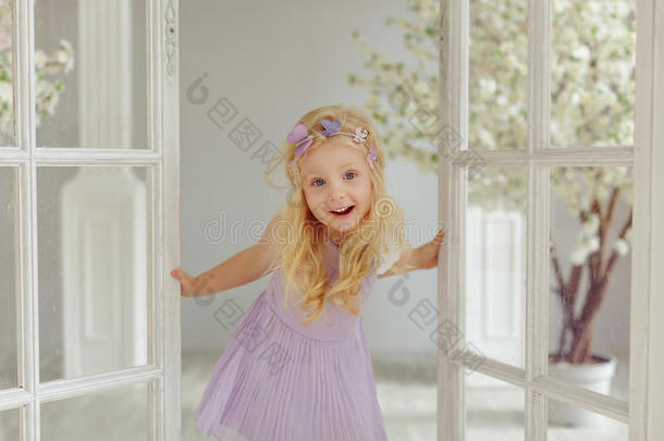迷人的小的亚麻色的女孩微笑反对白色的门采用光英文字母表的第19个字母