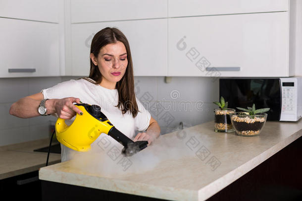 女人清洁厨房和蒸汽清洁剂
