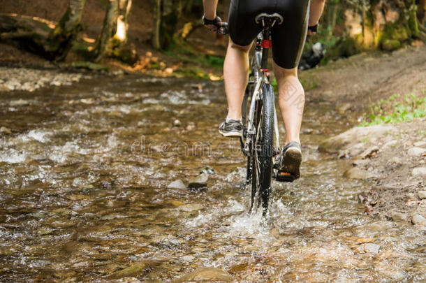 山骑自行车的人超速行驶通过森林河流