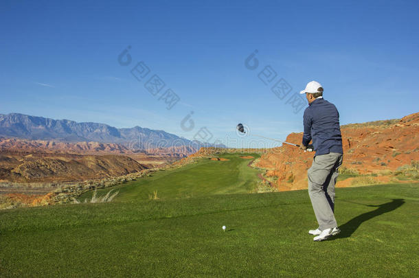 男人演奏高尔夫球向一be一utiful风景优美的沙漠高尔夫球课程