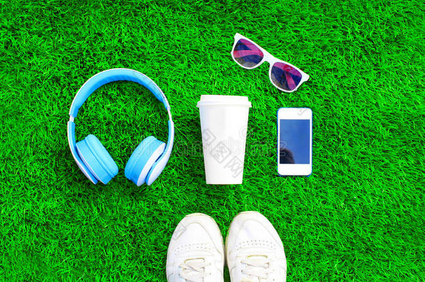 蓝色耳机,白色的智能手机,杯子关于成果果汁和潜行