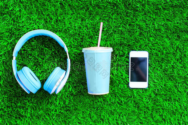 蓝色耳机,白色的智能手机,杯子关于成果果汁向一绿色的
