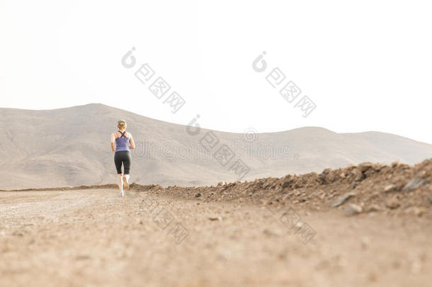 运动员的女士慢跑进入<strong>中距离</strong>沙漠泥土路