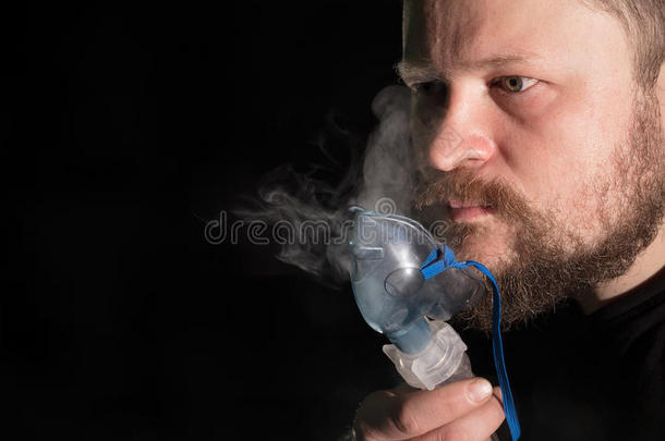 男人呼吸通过喷雾器面具