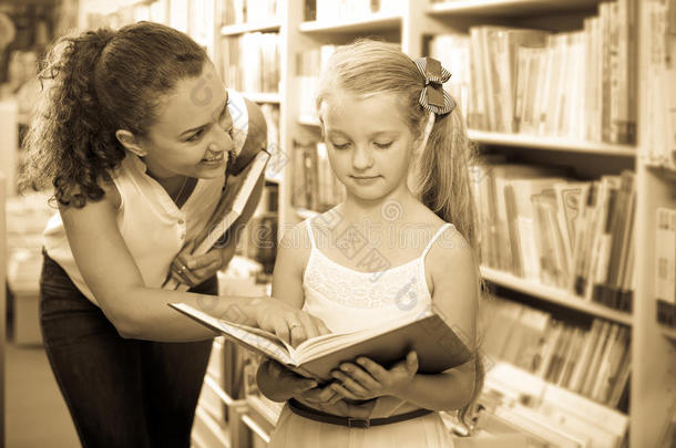 女人展映敞开的书向小的女孩