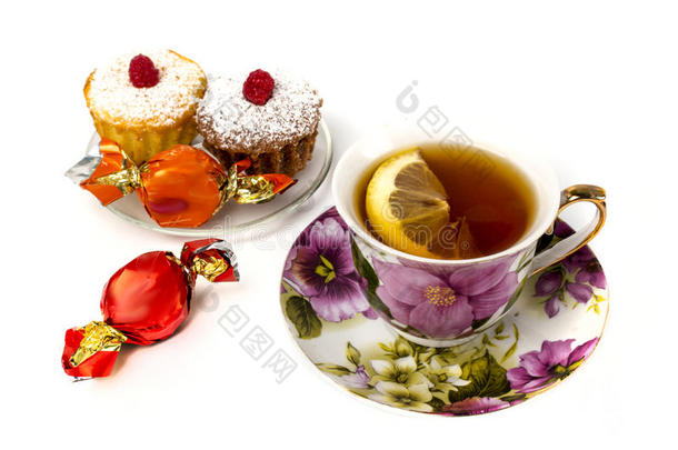 马克杯关于茶水和柠檬和和两个纸杯蛋糕