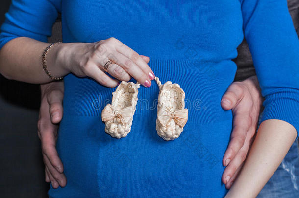 对白色的怀孕的女人和婴儿毛线鞋向肚子.
