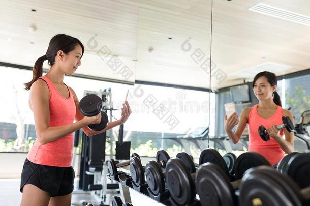 女人练习举起重量和茨金自拍照采用健身房