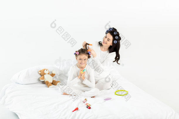 母亲采用卷发的人curl采用g头发向幸福的小的女儿向床