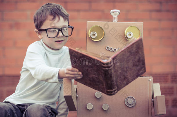 num.一小的男孩阅读向机器人从卡纸板盒在户外.