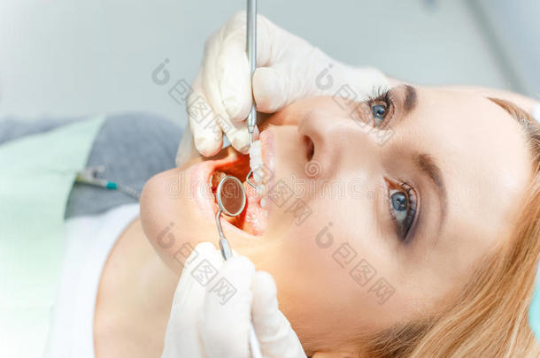 部分的看法关于白肤金发碧眼女人女人在牙齿的检查在上面有样子的在上面