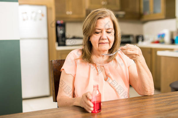 退休的女人喝饮料一勺关于<strong>咳嗽糖浆</strong>