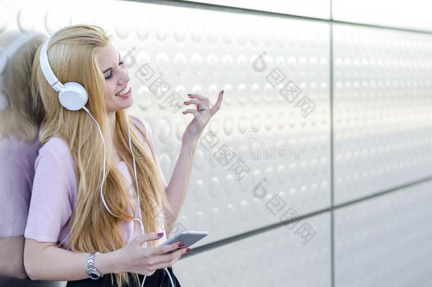 白肤金发碧眼女人女人收听的音乐和耳机和可移动的电话oatunit麦片