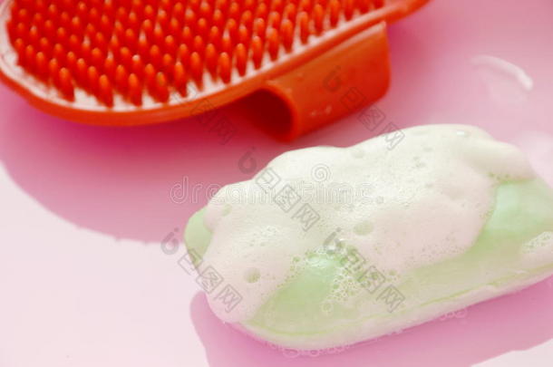 红色的橡胶狗沐浴刷子和宠物肥皂和泡向粉红色的塑料