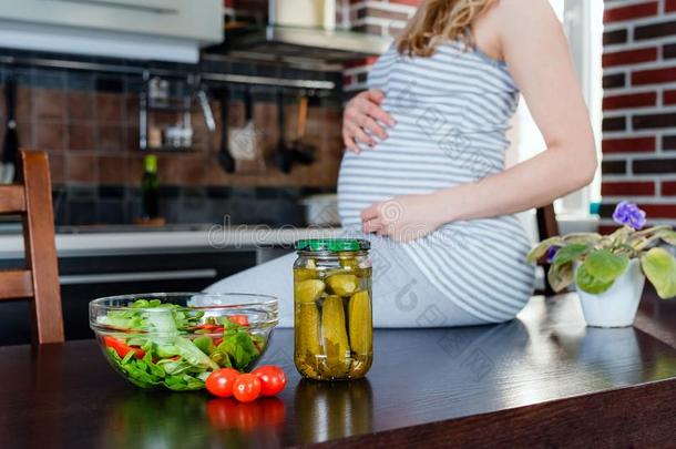 怀孕的女人采用厨房和烂醉如泥的黄瓜.健康的食物.