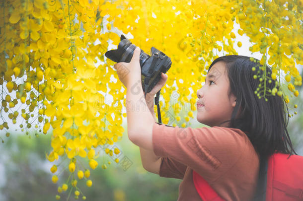亚洲人女孩拿照片和盛开的黄色的花