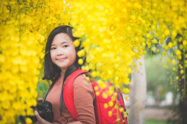 亚洲人女孩拿照片和盛开的黄色的花
