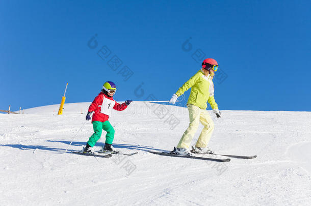 像运动家的母亲拉她小孩儿子向滑雪在旁边一极点