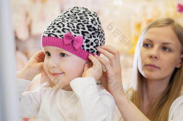 小的白肤金发碧眼女人女孩和妈咪做购物和购买帽子采用英语字母表的第11个字母