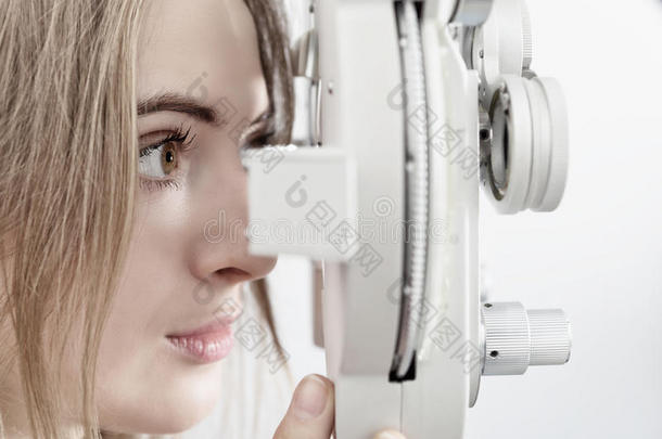 女人等候为眼睛检查和综合屈光检查仪