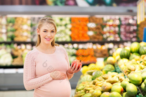 幸福的怀孕的女人和石榴在食品杂货店