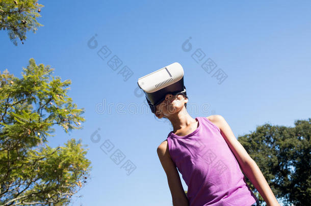 女孩使用VirtualReality虚拟现实戴在头上的耳机或听筒采用指已提到的人公园
