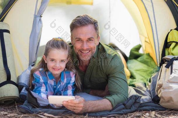 父亲和女儿使用可<strong>移动</strong>的电话在期间静止的采用<strong>帐篷</strong>