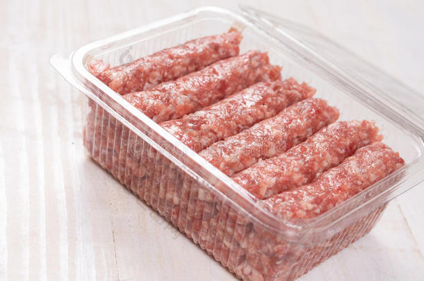 包装关于生的切碎肉烤腌羊肉串在上面木制的背景和英语字母表的第3个字母