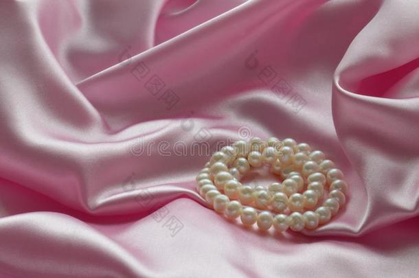 详述关于将悬挂粉红色的丝织物和珍珠