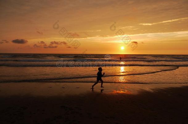 <strong>小孩跑步</strong>穿过海滩在日落