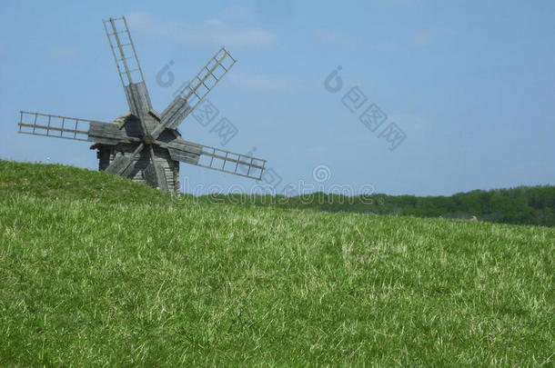 老的木制的风车.风车和新鲜的绿色的草和清楚的