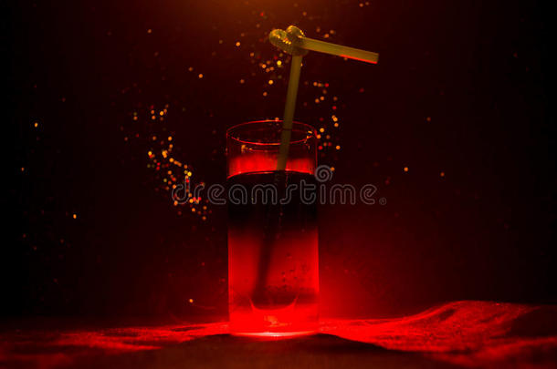 玻璃关于红色的酒精的鸡尾酒向黑暗的背景和烟一