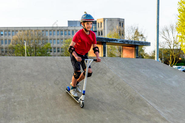 一天看法青少年男孩骑马小型摩托车向溜冰操场