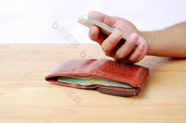 棕色的钱包和可移动的电话采用h和向木材背景.