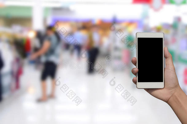 变模糊照片和智能手机向购物购物中心背景.