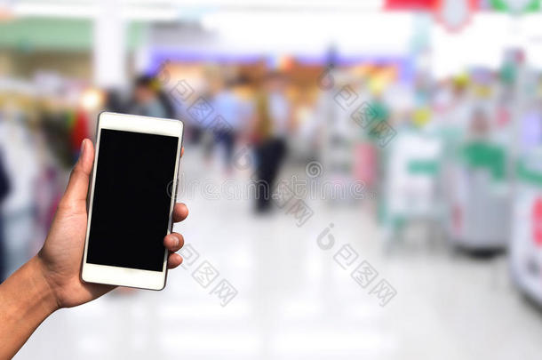 变模糊照片和智能手机向购物购物中心背景.