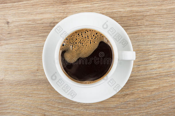 黑的咖啡豆采用杯子和茶杯托向木制的表