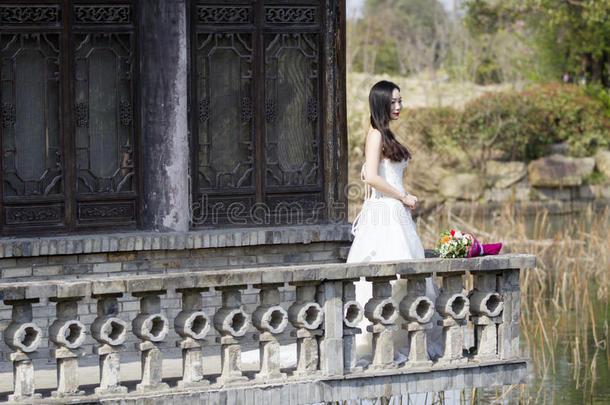 一女人和白色的婚礼衣服支撑新婚的花束台采用一