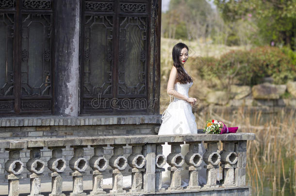一女人和白色的婚礼衣服支撑新婚的花束台采用一