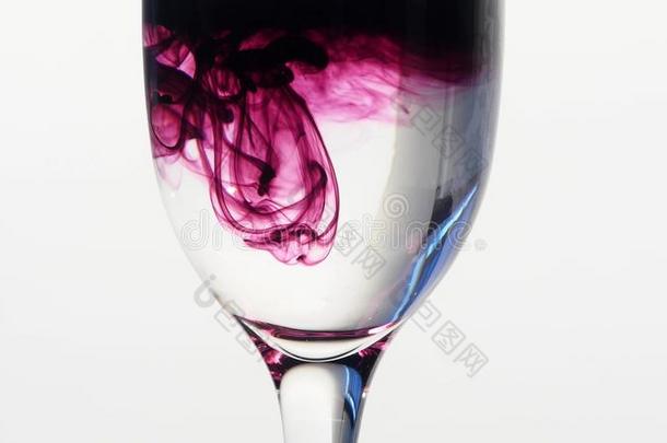 紫色的墨水滴下进入中玻璃关于平原水