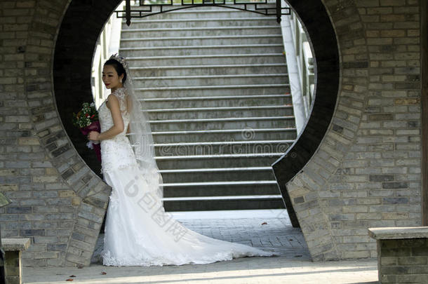 新娘拿住新婚<strong>的</strong>花束和白色<strong>的</strong>婚礼衣服在近处一砖