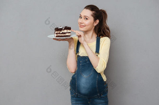 微笑的年幼的怀孕的女人佃户租种的土地盘子和巧克力蛋糕