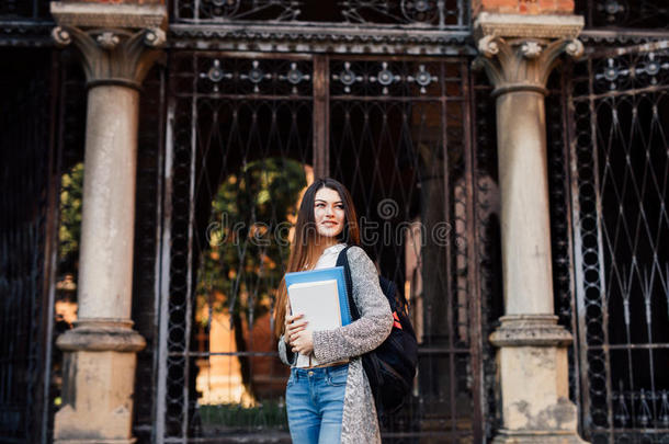 微笑的漂亮的年幼的女人学生和背包步行户外的