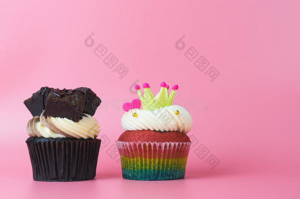 2纸杯蛋糕巧克力和彩虹纸杯蛋糕向粉红色的背景