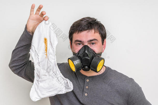 父亲和气体面具替换发出难闻气味的尿布