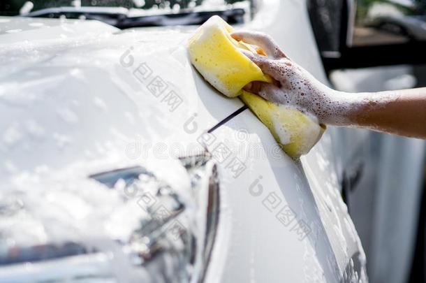 女人手和黄色的海绵洗涤汽车