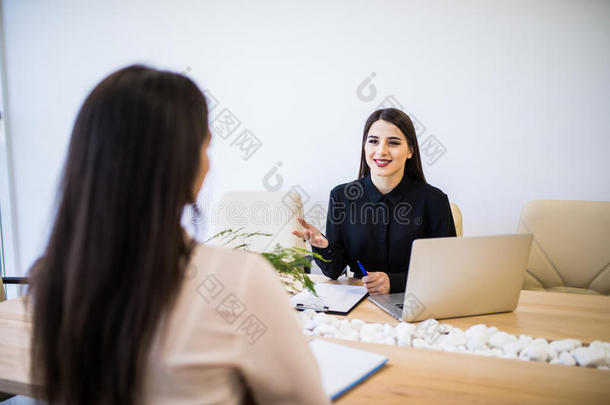 两个<strong>商</strong>业女人一次在书桌:顾客和顾问讲话