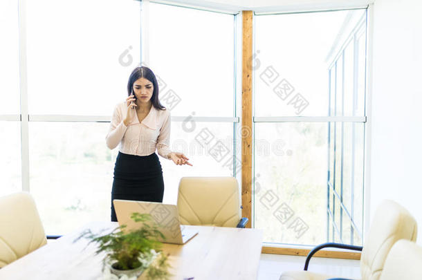 商业女人讲话在旁边可移动的电话和看在便携式电脑<strong>再来一次</strong>
