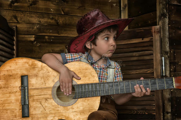 小的男孩采用cow男孩帽子和吉他